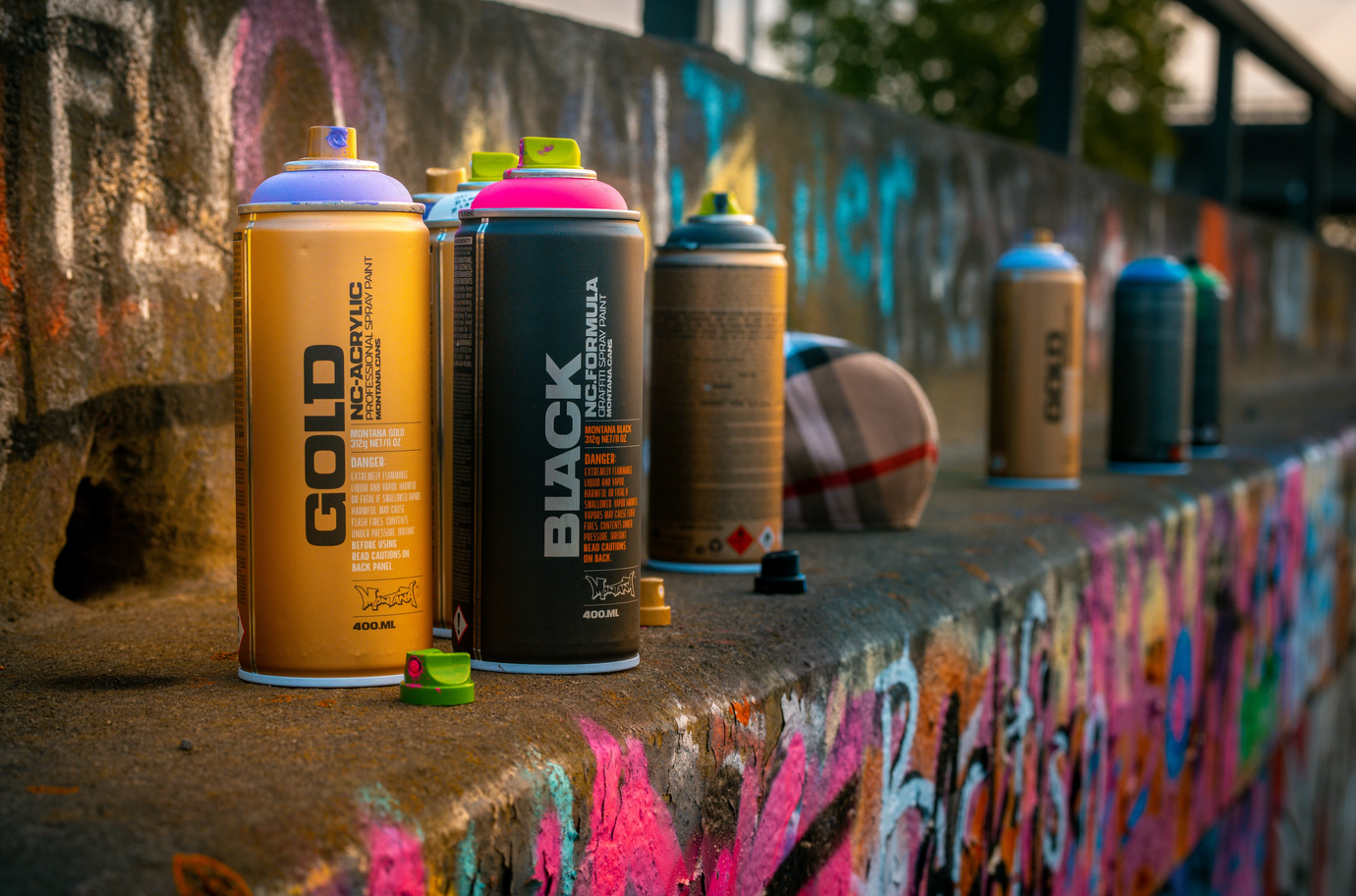 Spray paint cans displayed outdoors on a place covered by graffitis.