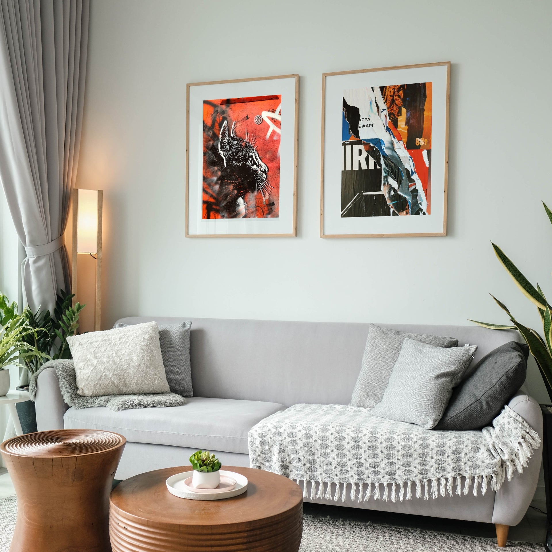 A living room with two framed posters on the wall above a grey couch