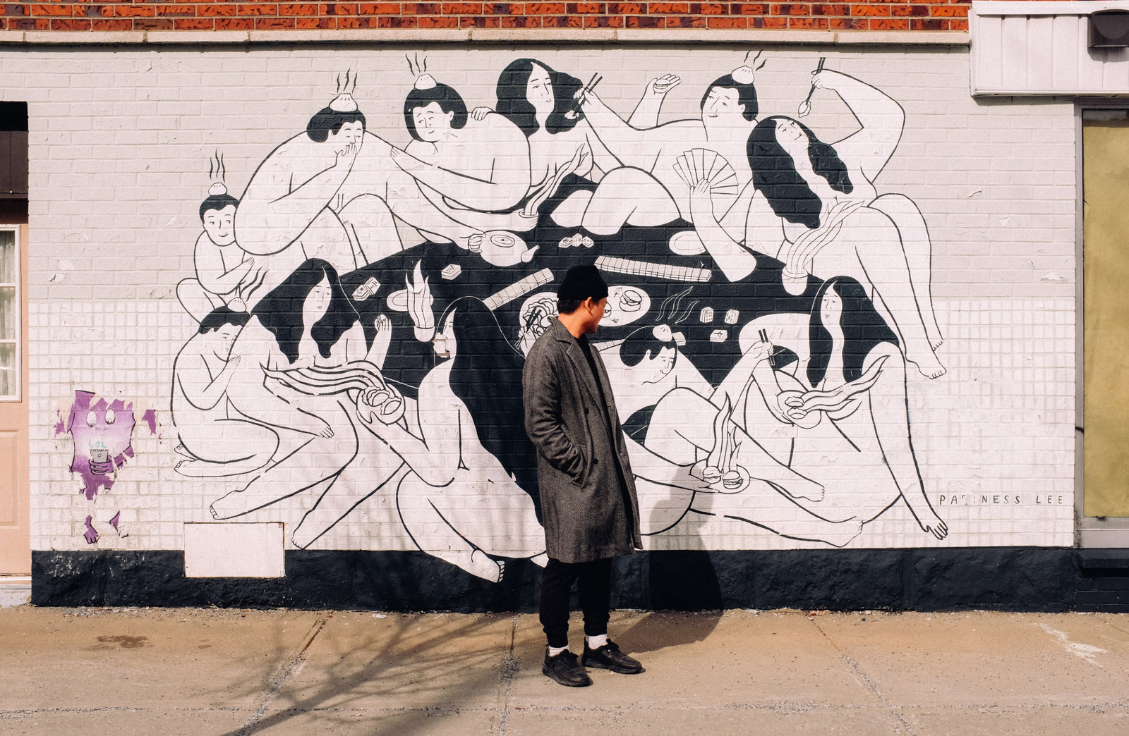 Someone on the sidewalk in front of a black and white graffiti