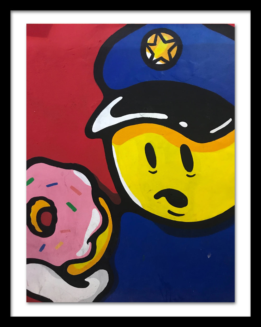 A poster in a black frame that depicts a policeman holding a doughnut