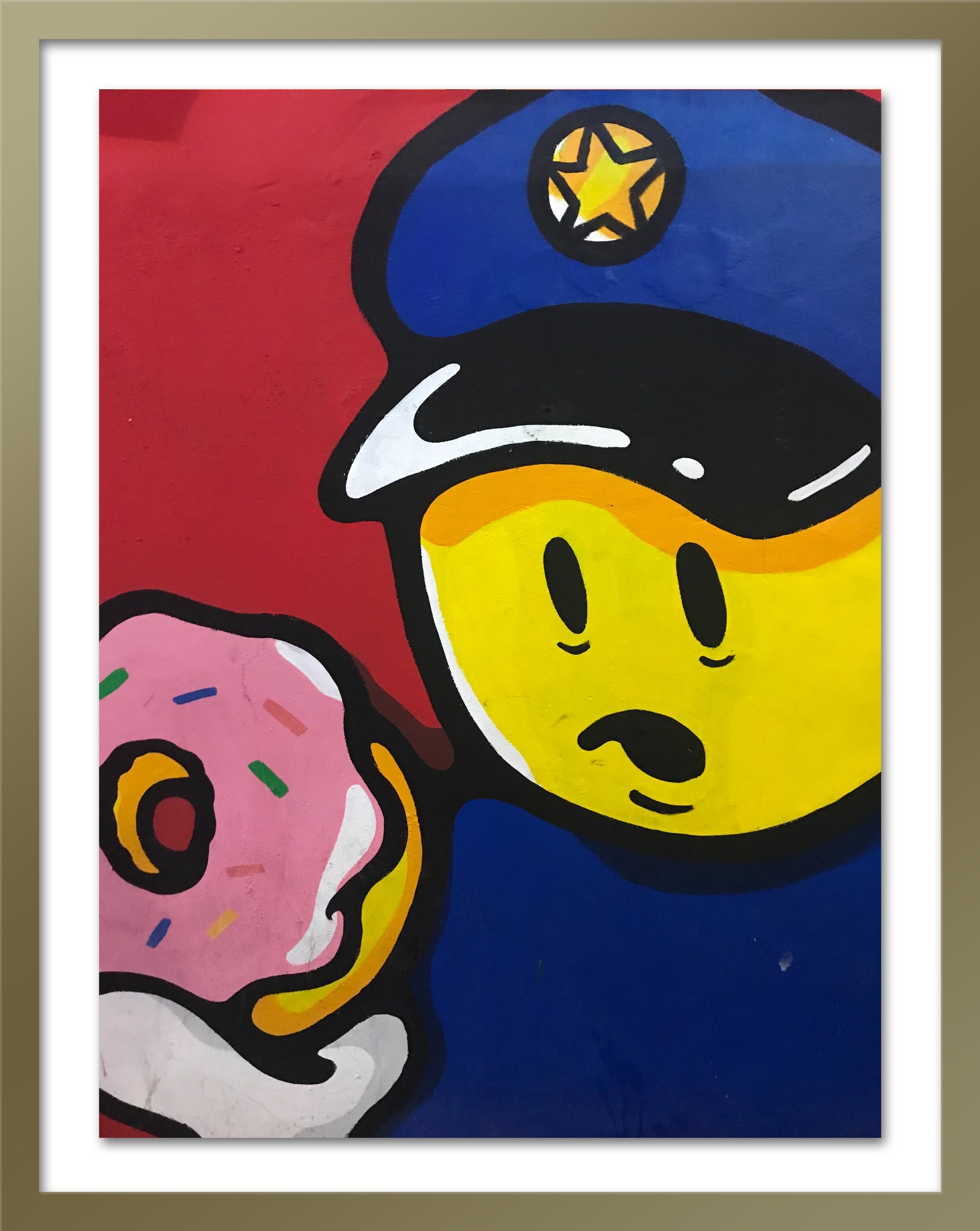 A poster in a gold frame that depicts a policeman holding a doughnut