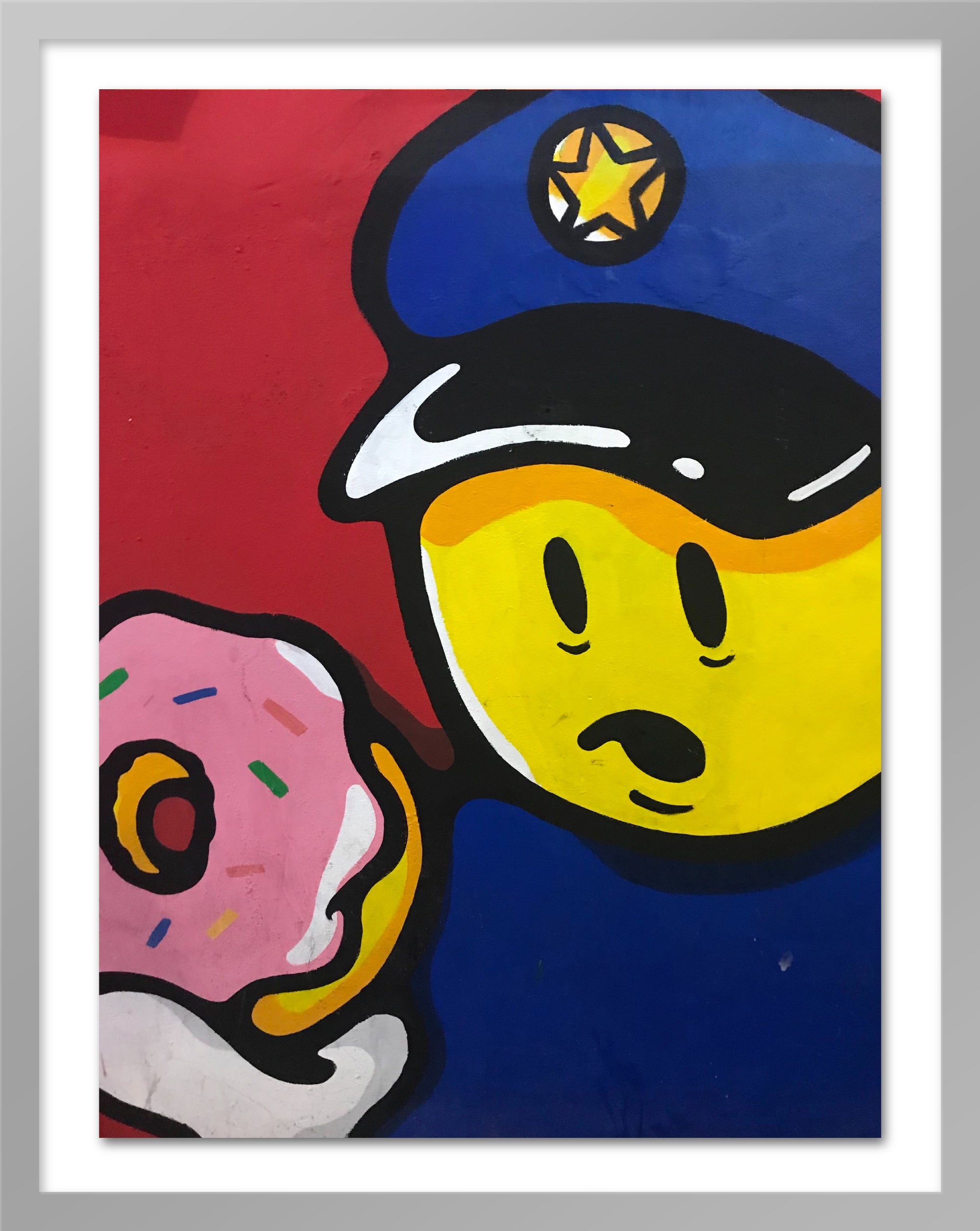 A poster in a silver frame that depicts a policeman holding a doughnut