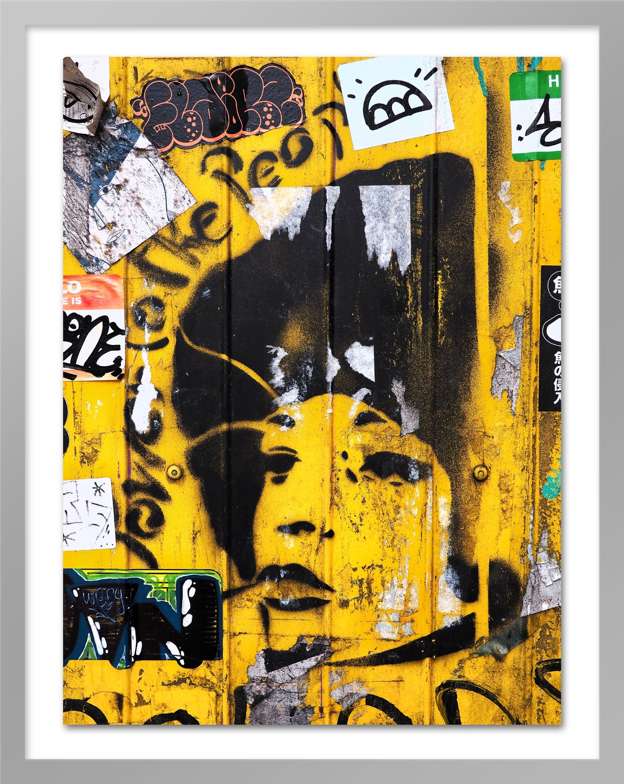 A poster that depicts the portrait of a woman painted with a stencil over a yellow wall