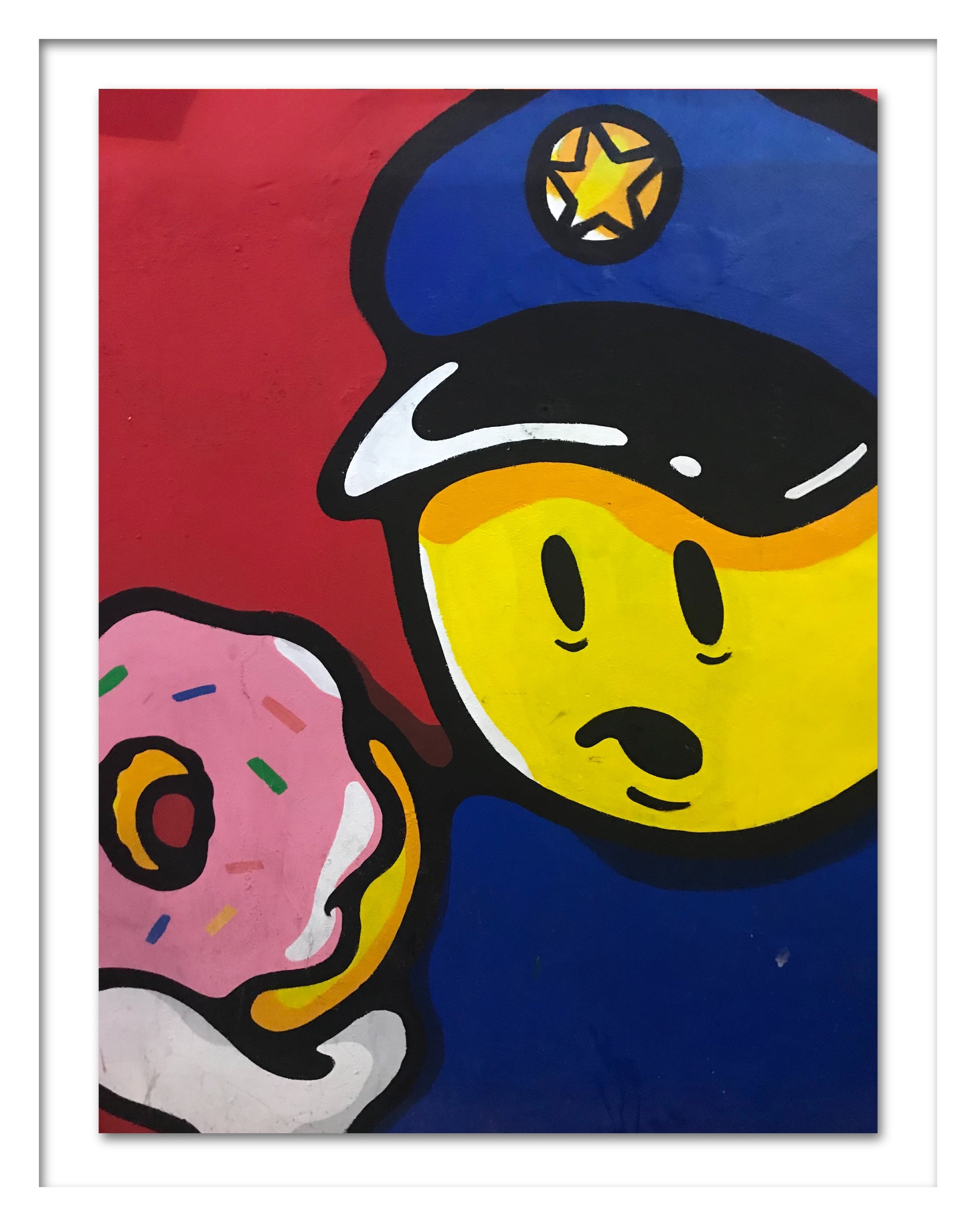 A poster in a white frame that depicts a policeman holding a doughnut