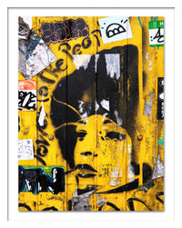 A poster that depicts the portrait of a woman painted with a stencil over a yellow wall